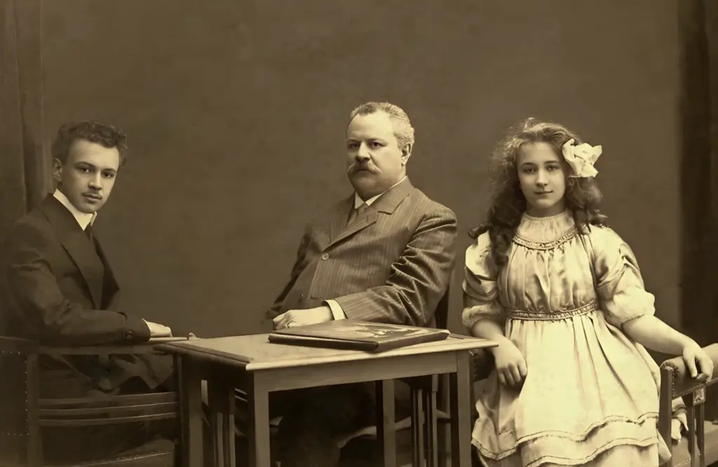 Vintage sepia family portrait of the founder of Elektrosal factory, with his son and daughter at a table, early 20th century.