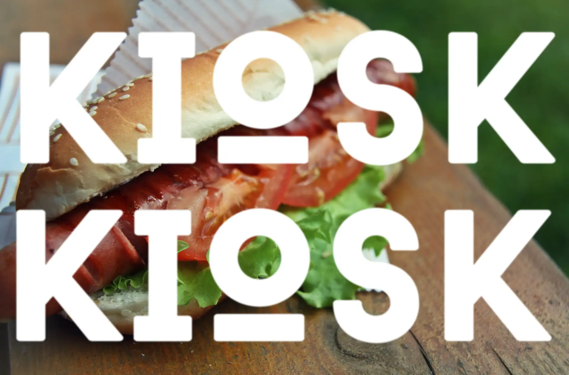Close-up of hot dog under bold KIOSK logo graphic