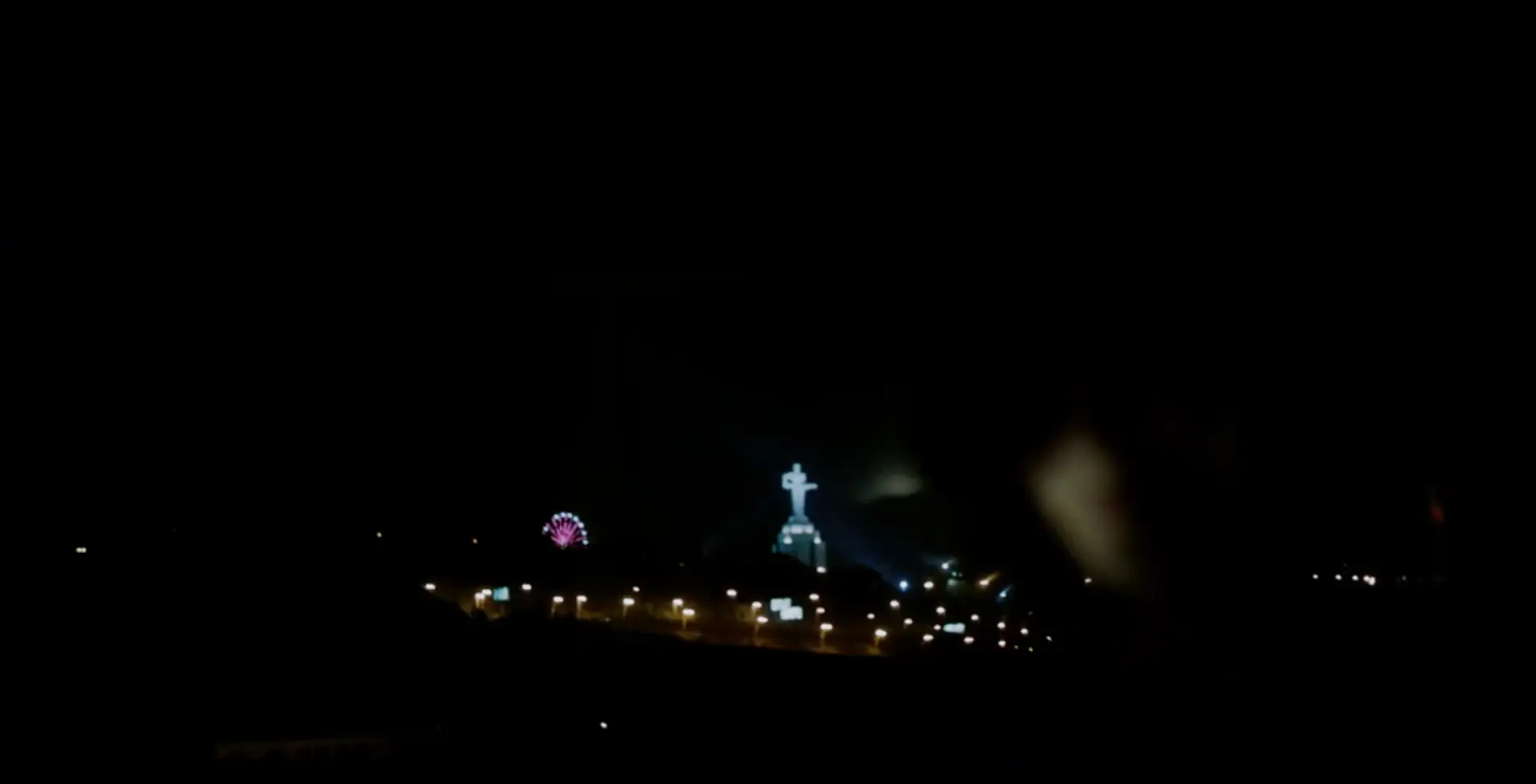 Night view of Yerevan with illuminated Mother Armenia statue, ferris wheel, and city lights.