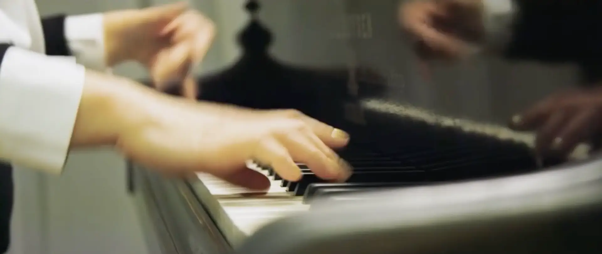 Close-up of pianist’s hands playing a grand piano at a hotel lounge.