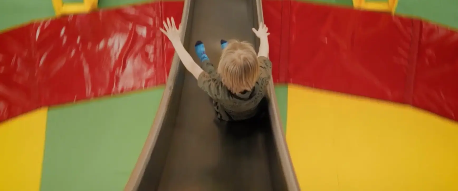 Young boy sliding down a colorful slide at Chudo-Park family entertainment center.