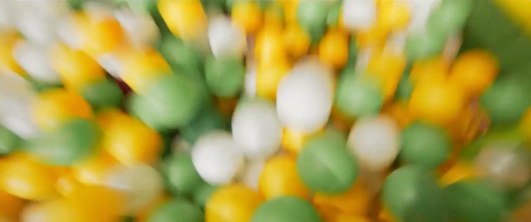 Colorful green, yellow, and white plastic balls in a Chudo-Park play area ball pit.